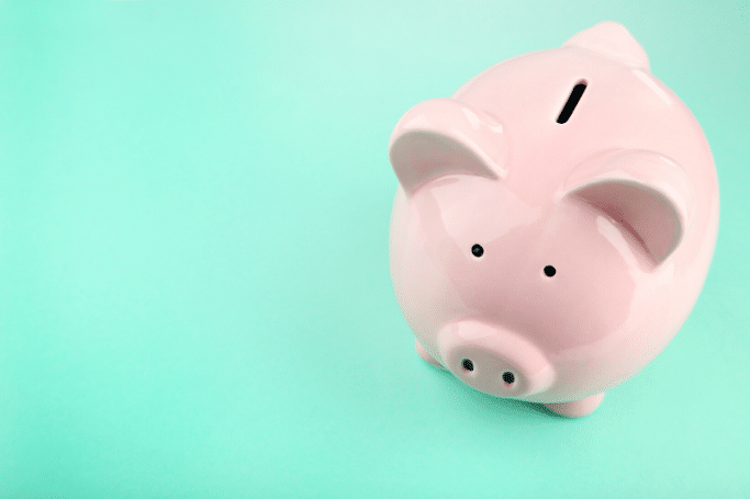 pink piggy bank on light teal background