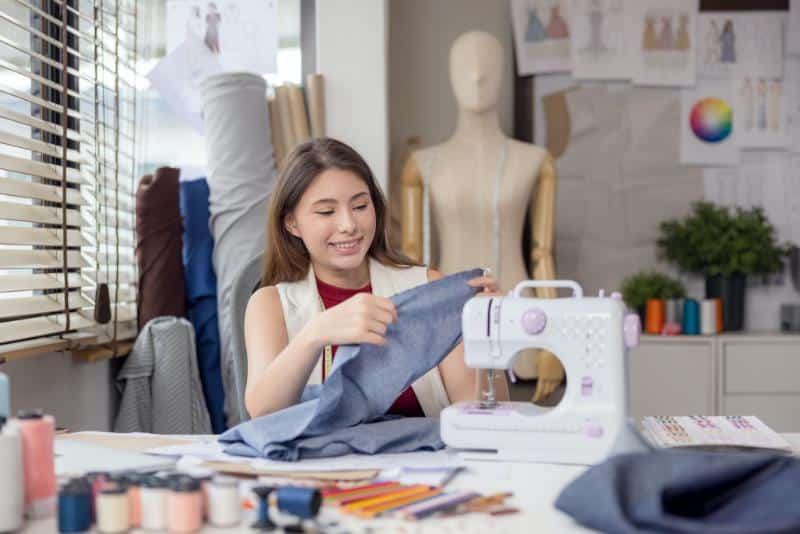 young woman using a sewing machine to design clothes