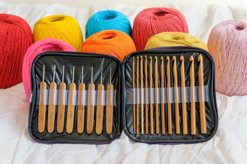 crochet hooks and needles with various colors of yarn