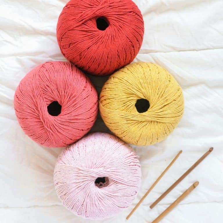 crochet needles and yarn in various pinks and yellow